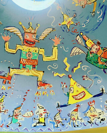 Another close-up photo of Hamish Kilgour's painting at WFMU showing a man with a king's crown and wings against a field of blue. His arms and legs are extended at right angles and he appears to be wearing a shirt that says "WFMU" on it. In the lower right is a yellow triangle with eyes and a toothy smile, with arms extending out from the middle of each side and legs extending out from each bottom corner.