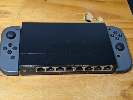 Nintendo's attachable gamepads placed at the left and right sides of a Netgear 8-port Gigabit Ethernet switch.