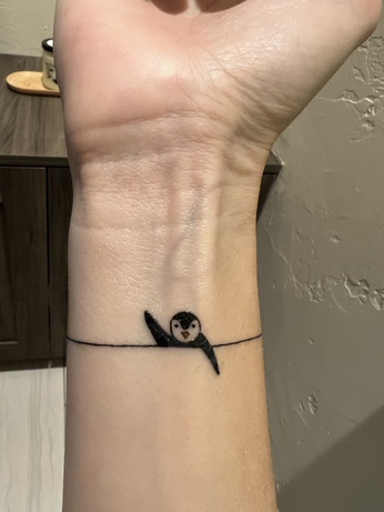 Cute little penguin on a woman’s wrist 