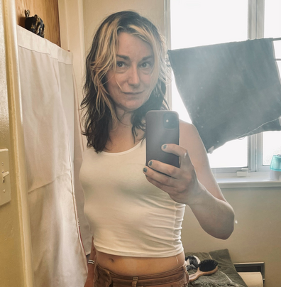 Trans woman with generally available navel looking soulfully at the mirror