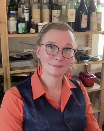 Nicole is ready to deal: orange shirt, navy vest, chunky orange earrings. Missing: optimal arrangement of navy earrings, and orange headband. 